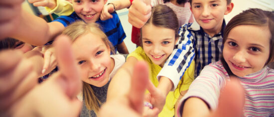 education, elementary school, learning, gesture and people concept - group of school kids and showing thumbs up in classroom